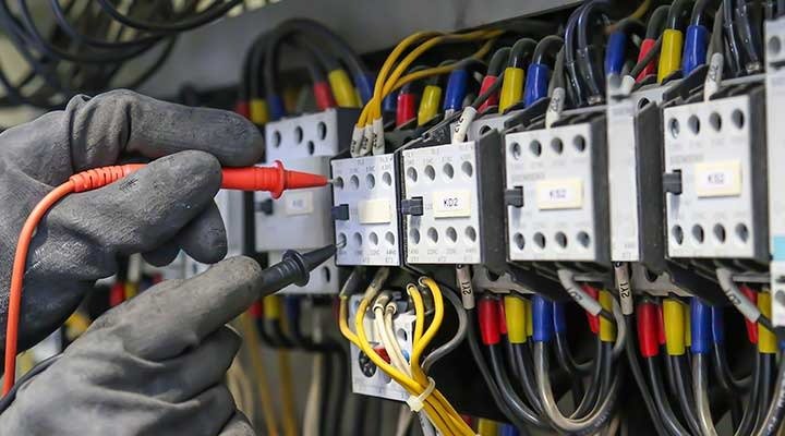 Electrician testing circuit breaker panel